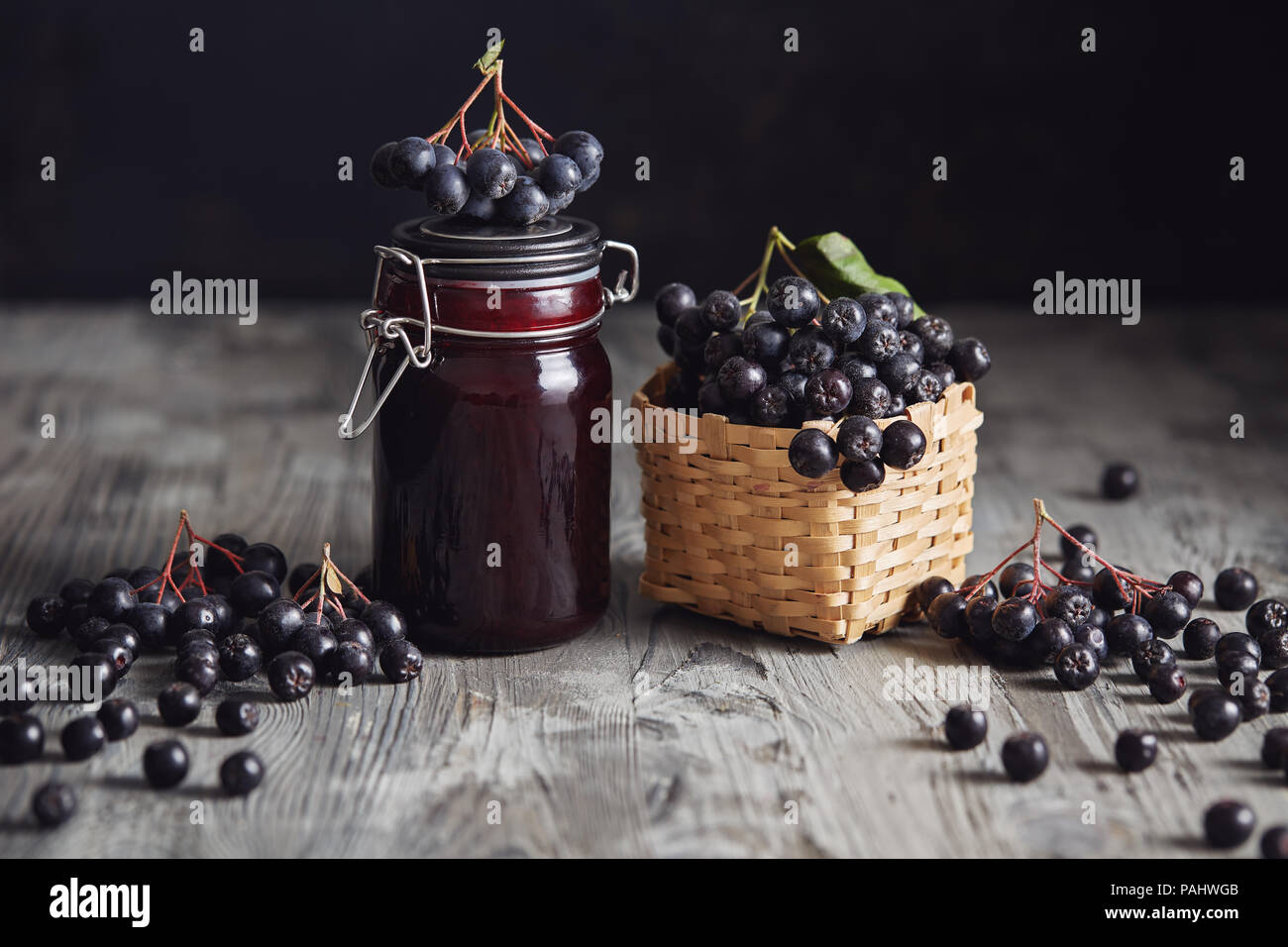 À côté de bourrage Aronia de baies fraîches. Aronia fait maison avec bol en verre de bourrage dans les baies fraîches aronia sur table en bois. Banque D'Images