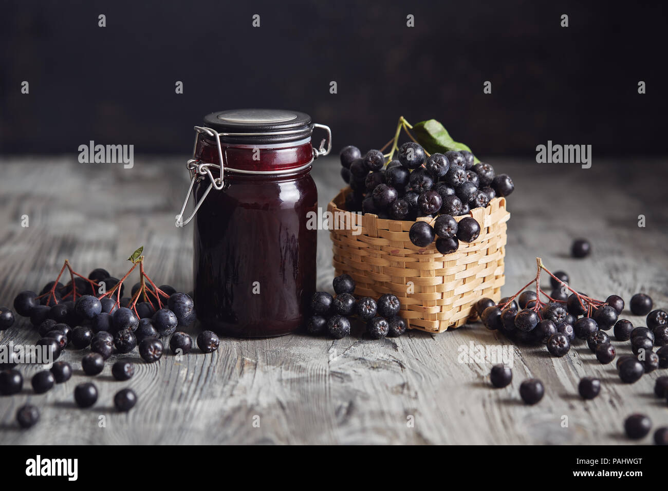 À côté de bourrage Aronia de baies fraîches. Aronia fait maison avec bol en verre de bourrage dans les baies fraîches aronia sur table en bois. Banque D'Images