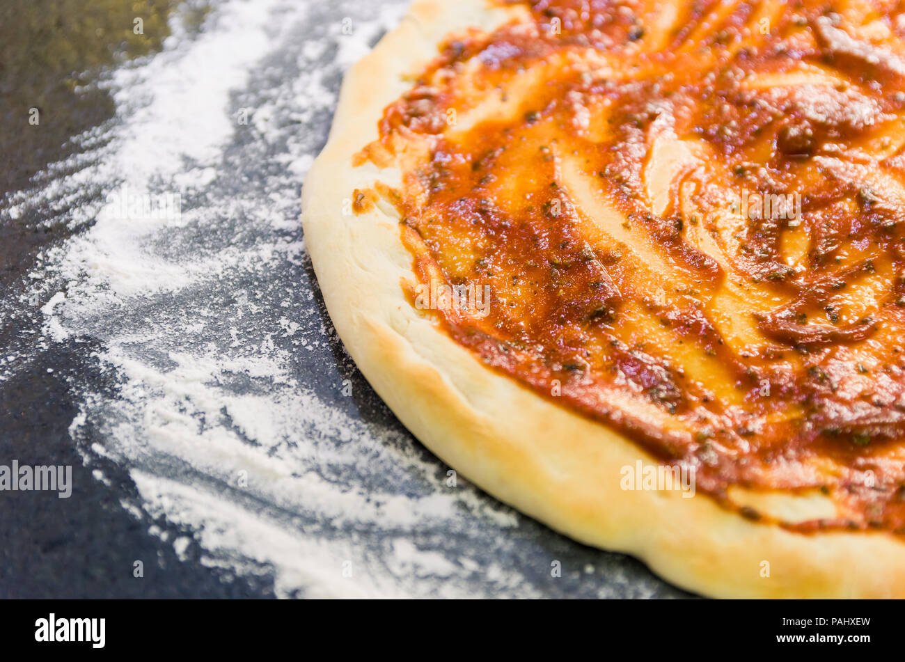La préparation de pizza, close-up de la pâte à pizza avec la sauce tomate. Banque D'Images