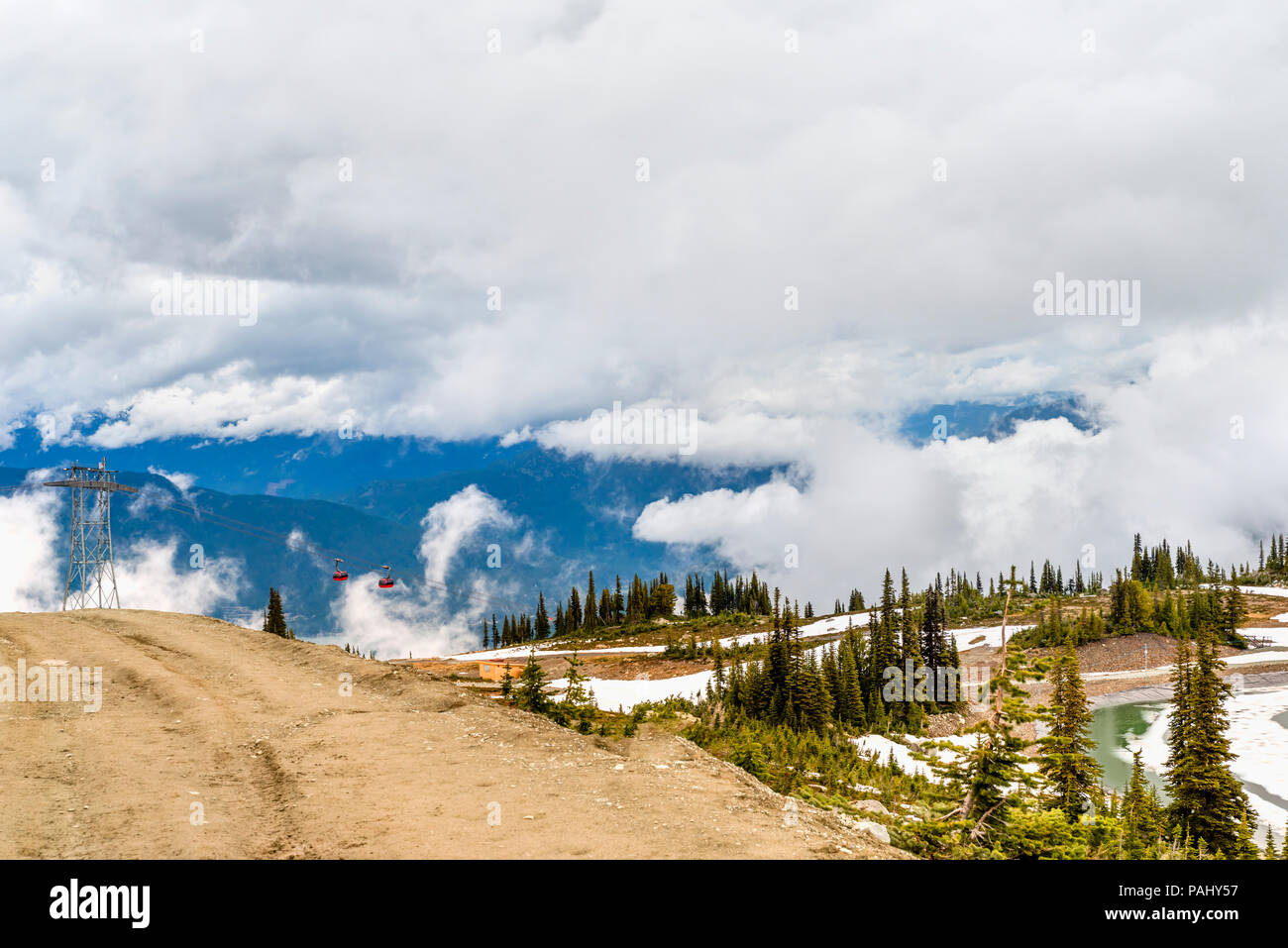 Vue depuis une route de campagne à épais, nuages bas dans les montagnes, couvertes d'arbres et de la neige au-dessus de la station de ski avec la télécabine de la télécabine et Banque D'Images