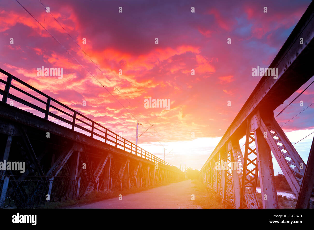 Lever du Soleil avec ciel spectaculaire au-dessus d'un pont de fer. Banque D'Images