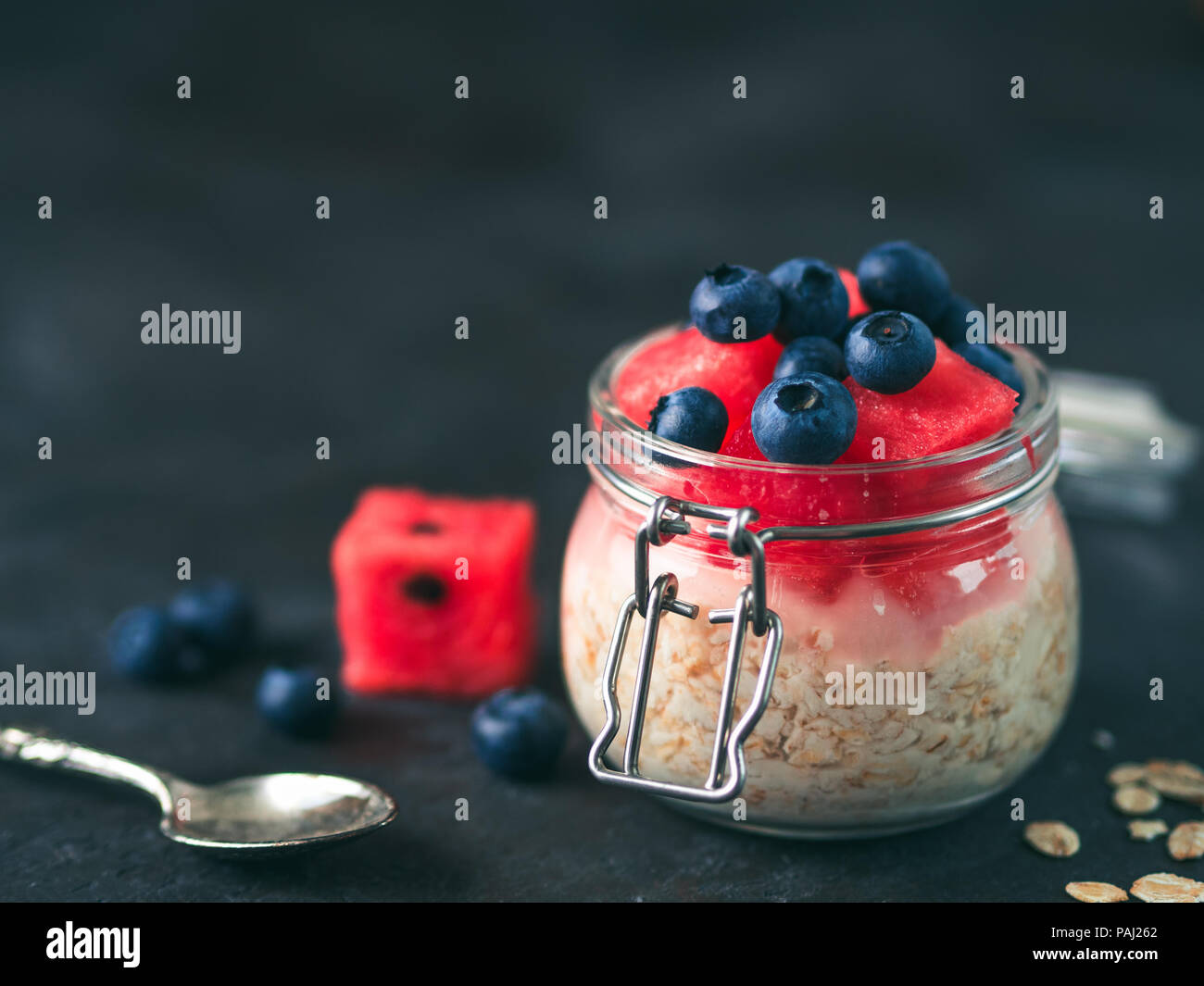 Petit-déjeuner sain et idée recette : du jour au lendemain de l'avoine avec des fruits frais et de baies dans un bocal en verre.La nuit d'avoine porridge avec pastèque,blueberry.Du jour au lendemain de l'avoine sur fond noir.Copier l'emplacement pour un texte Banque D'Images