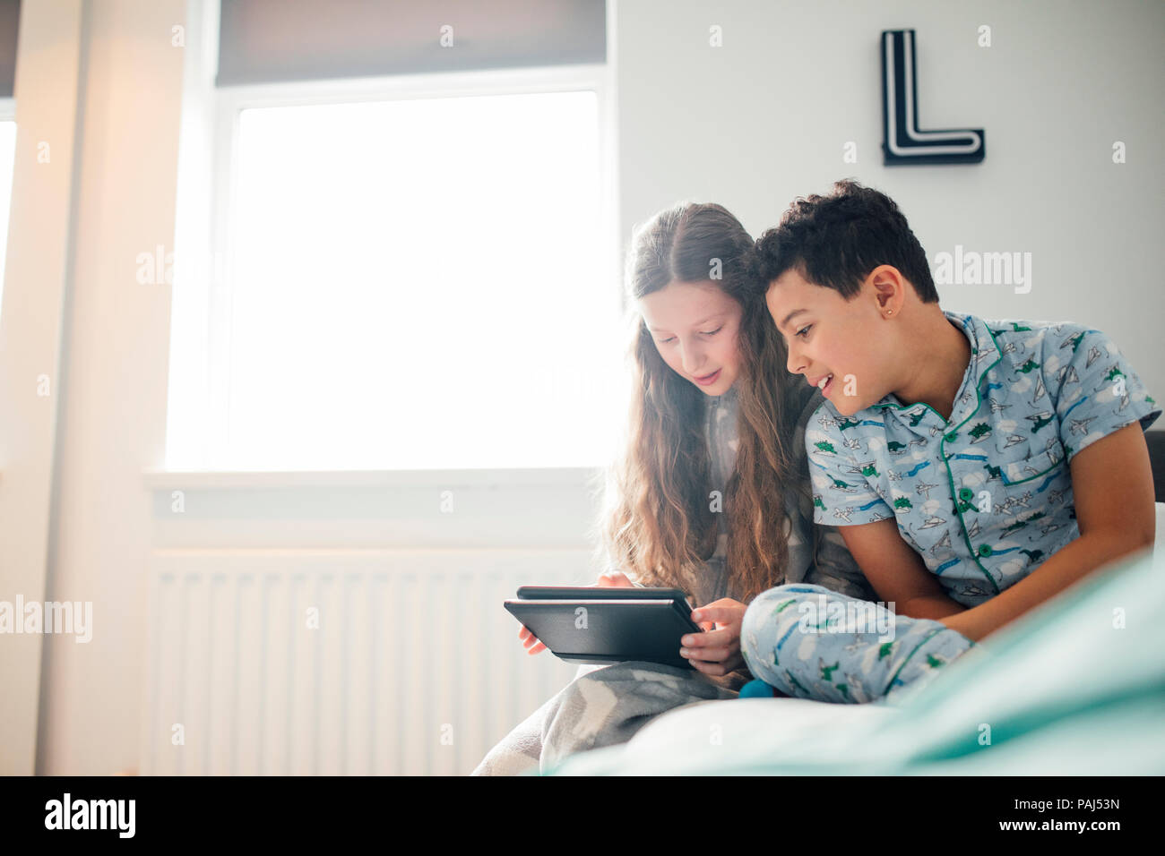 Petite fille et son frère sont à la recherche d'une tablette numérique à l'ensemble dans la chambre du garçon. Banque D'Images