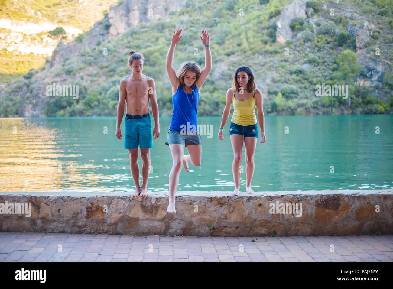 Les amis de sauter sur un remblai sur un lac turquoise dans les montagnes Banque D'Images