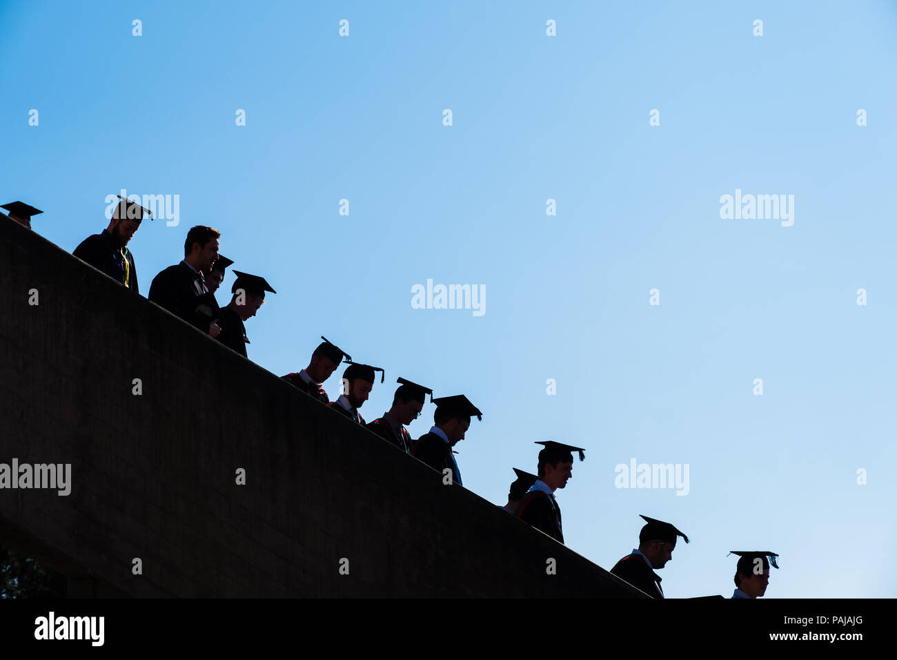 L'enseignement supérieur au Royaume-Uni : les finissants d'université d'Aberystwyth, à leurs conseils et le mortier traditionnel robes académiques noir. Silhouetted against a blue sky. Juillet 2018 Banque D'Images