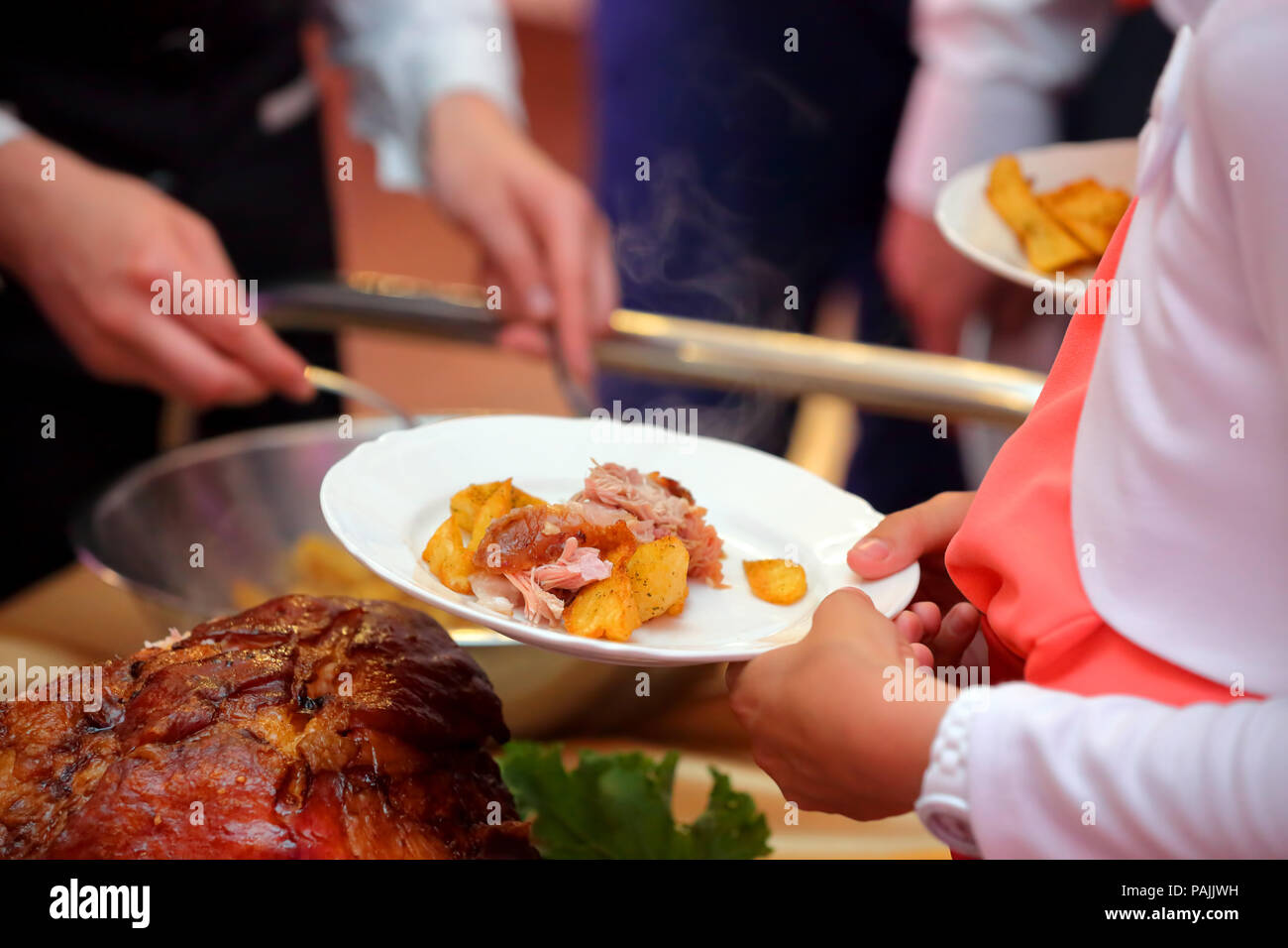 Serveur sert de viande rôtie et pommes de terre au four à la fête ou réception de mariage Banque D'Images