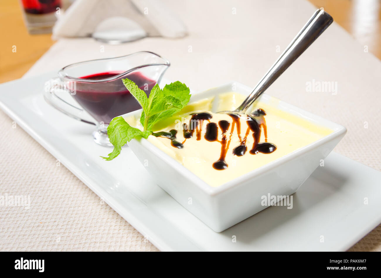 Crème brûlée catalane avec chocolat vanille menthe et de confiture de petits fruits sur une plaque rectangulaire blanche Banque D'Images