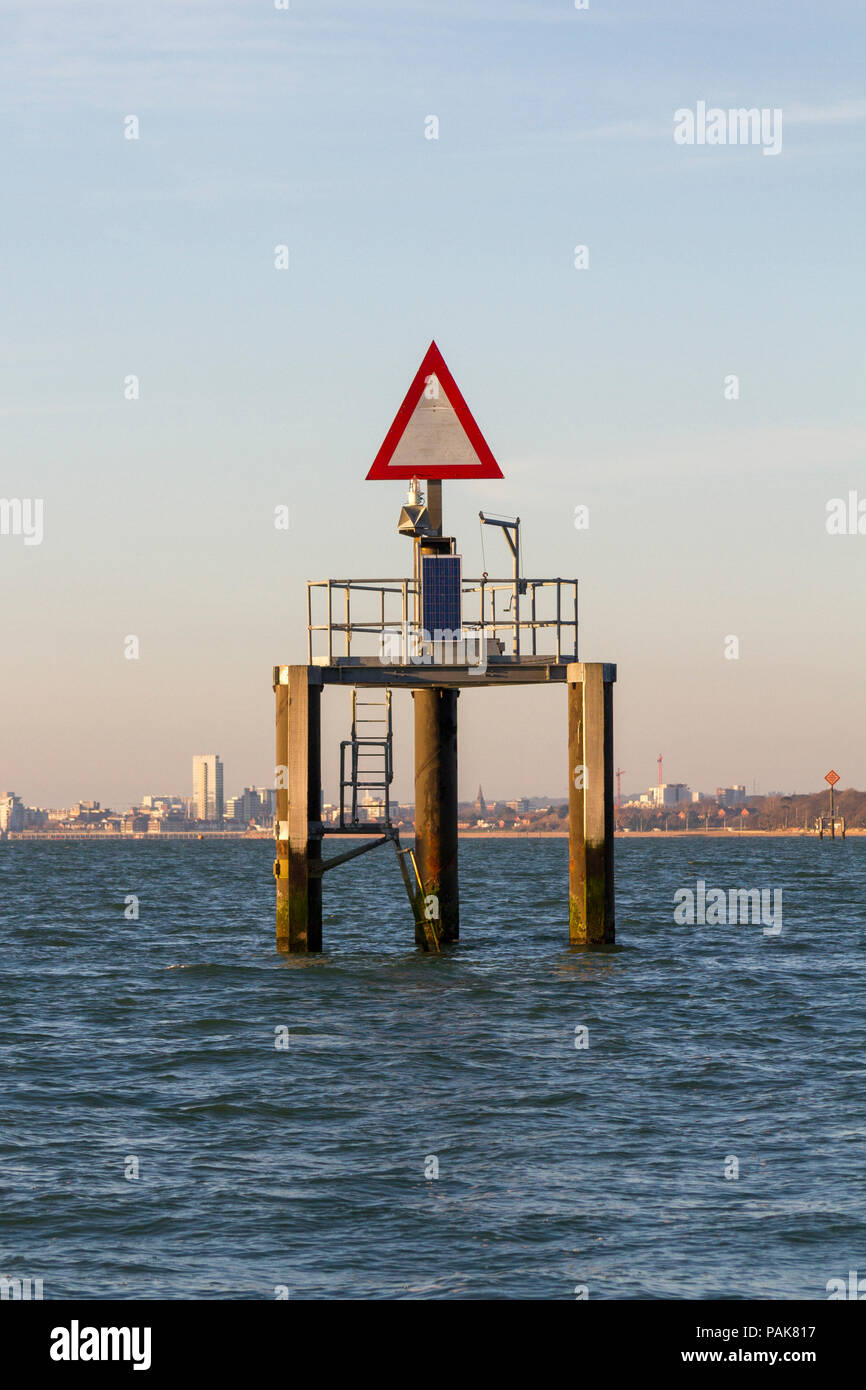 Signe de navigation (triangle rouge sur fond blanc) dans le Solent, UK près de raffinerie de pétrole. Banque D'Images
