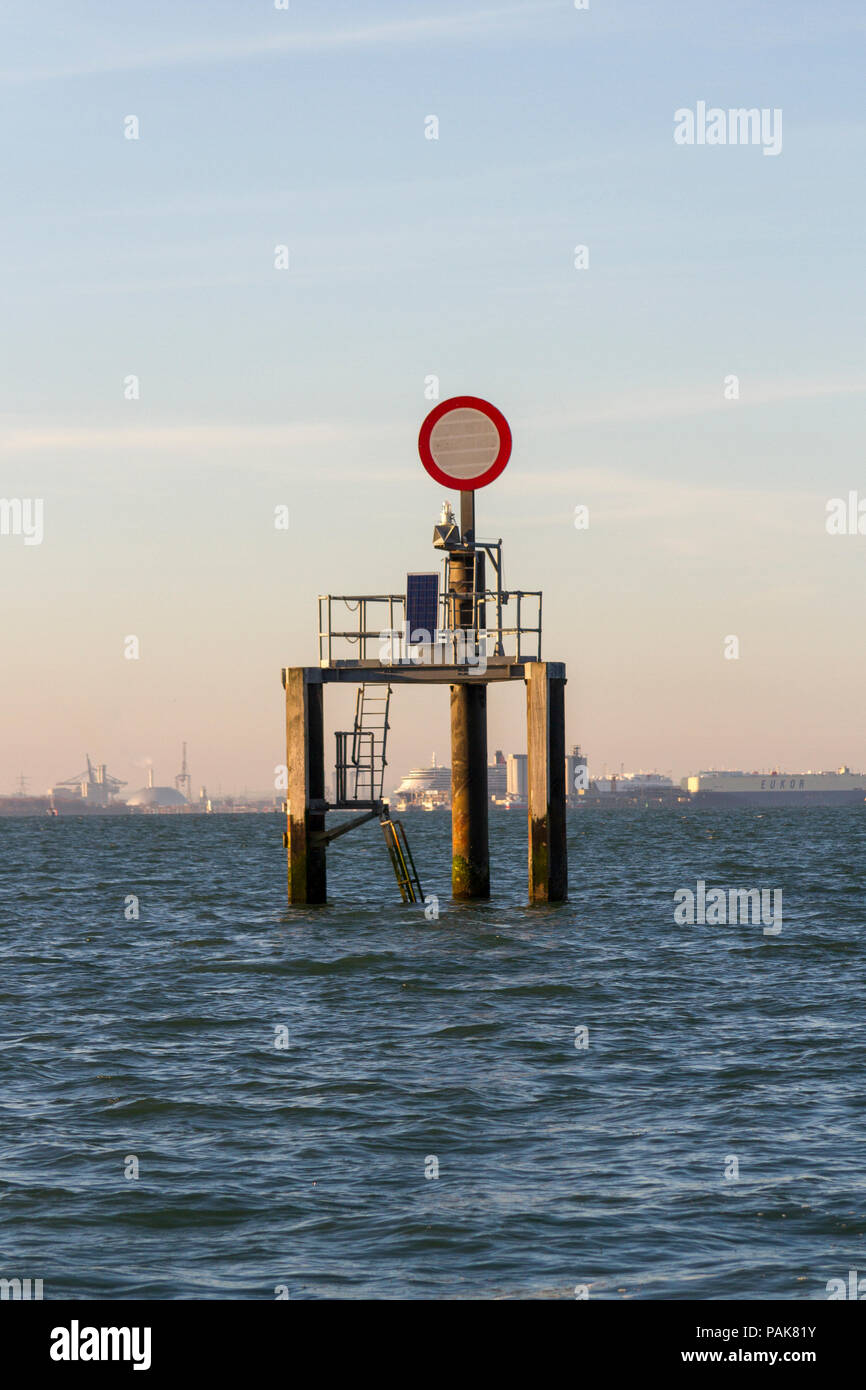 Signe de navigation (cercle rouge sur fond blanc) dans le Solent, UK près de raffinerie de pétrole. Banque D'Images