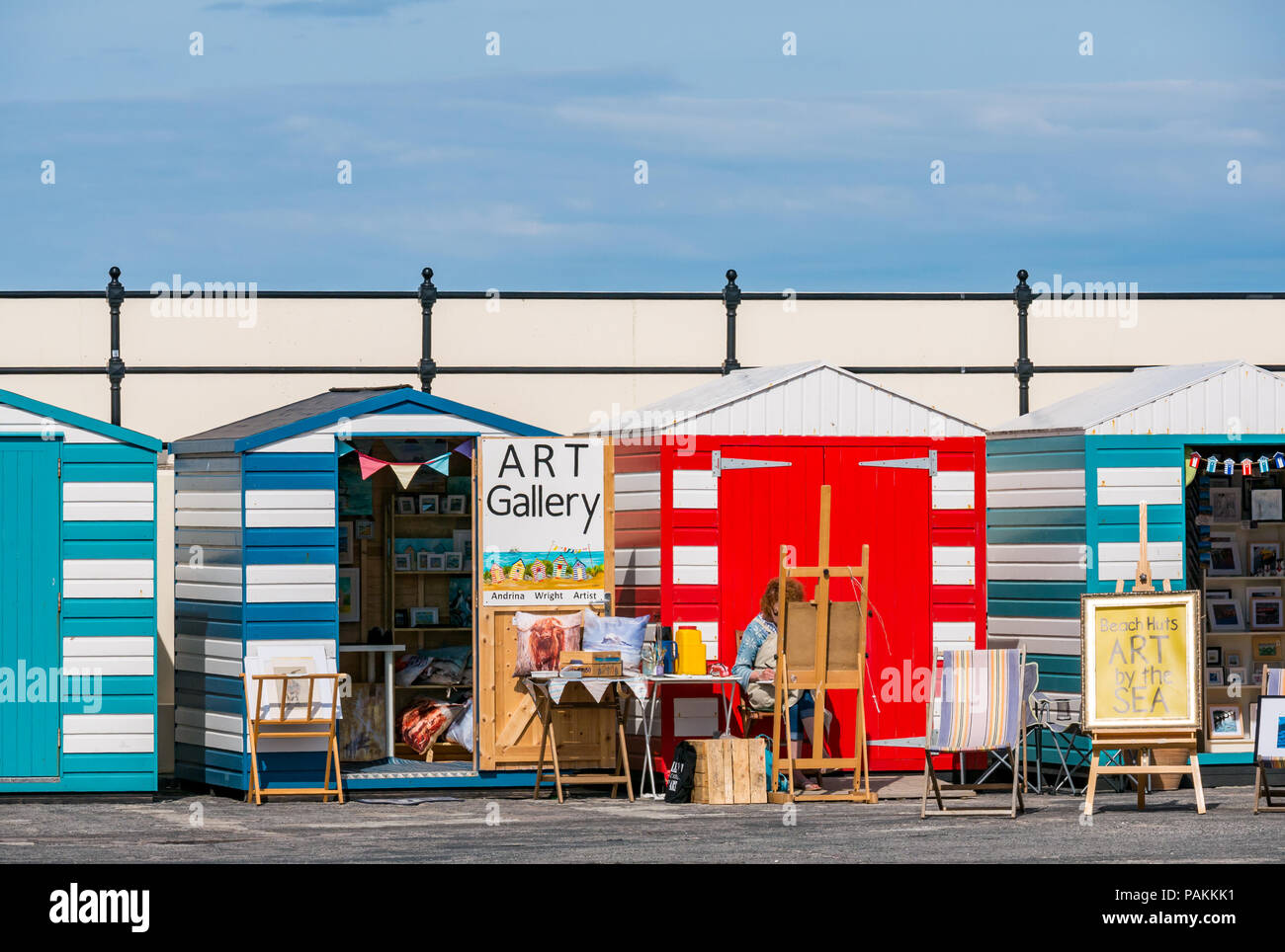 North Berwick, East Lothian, Écosse, Royaume-Uni, 24 juillet 2018. Météo au Royaume-Uni : un artiste au travail dans l'une des cabines de plage colorées s'est transformée en galerie d'art dans la région du port Banque D'Images