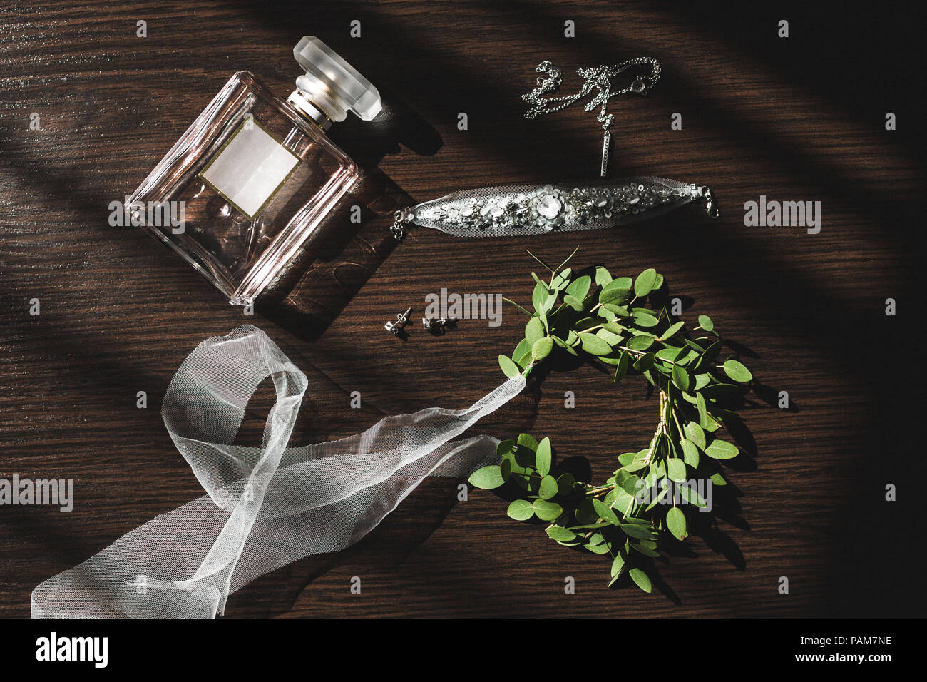 Mariage de la mariée, parfum, bijoux collier boucles d'oreilles, et une couronne verte avec des rubans sur table en bois Banque D'Images