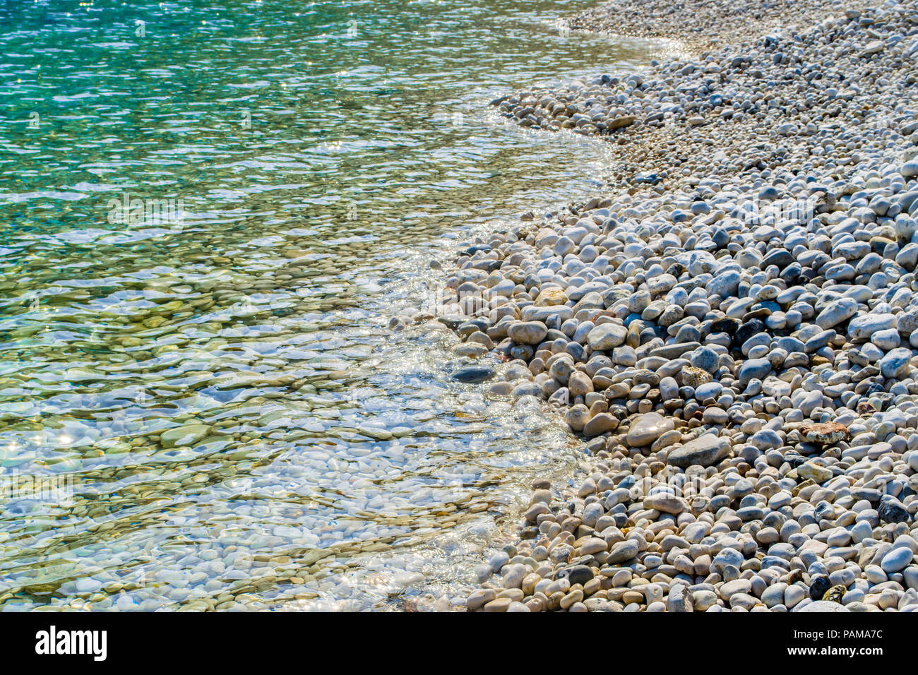 Les eaux cristallines de la mer turquoise d'une plage de galets. La plage de Poros en Grèce dans l'île Ionienne Leucade Banque D'Images