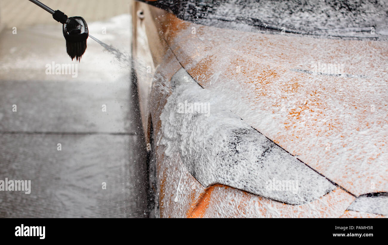 Lavage de voiture au lave-auto libre service. Shampoing mousse et gouttelettes de la brosse pour projecteur. Banque D'Images