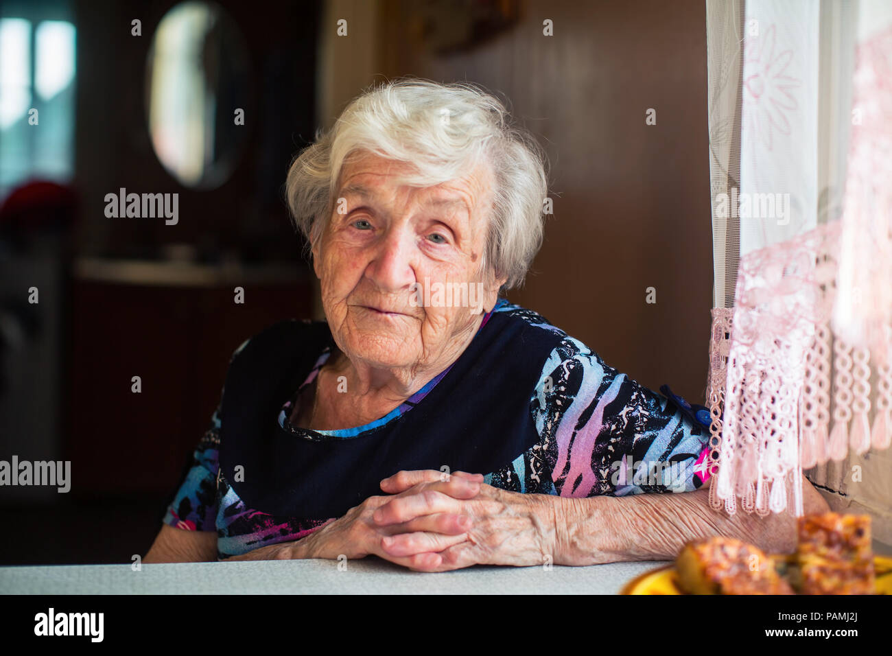 Portrait d'une femme âgée assise à la table. Banque D'Images