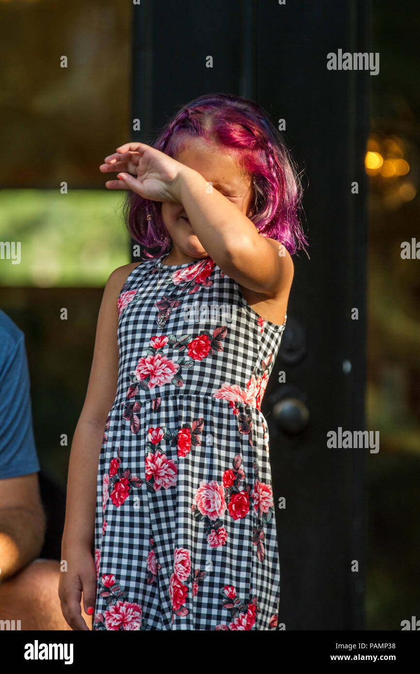 Fille aux cheveux teints en rouge vif, tenant main devant le visage, en combinaison de saut coloré. Communiqué de modèle # 114 Banque D'Images