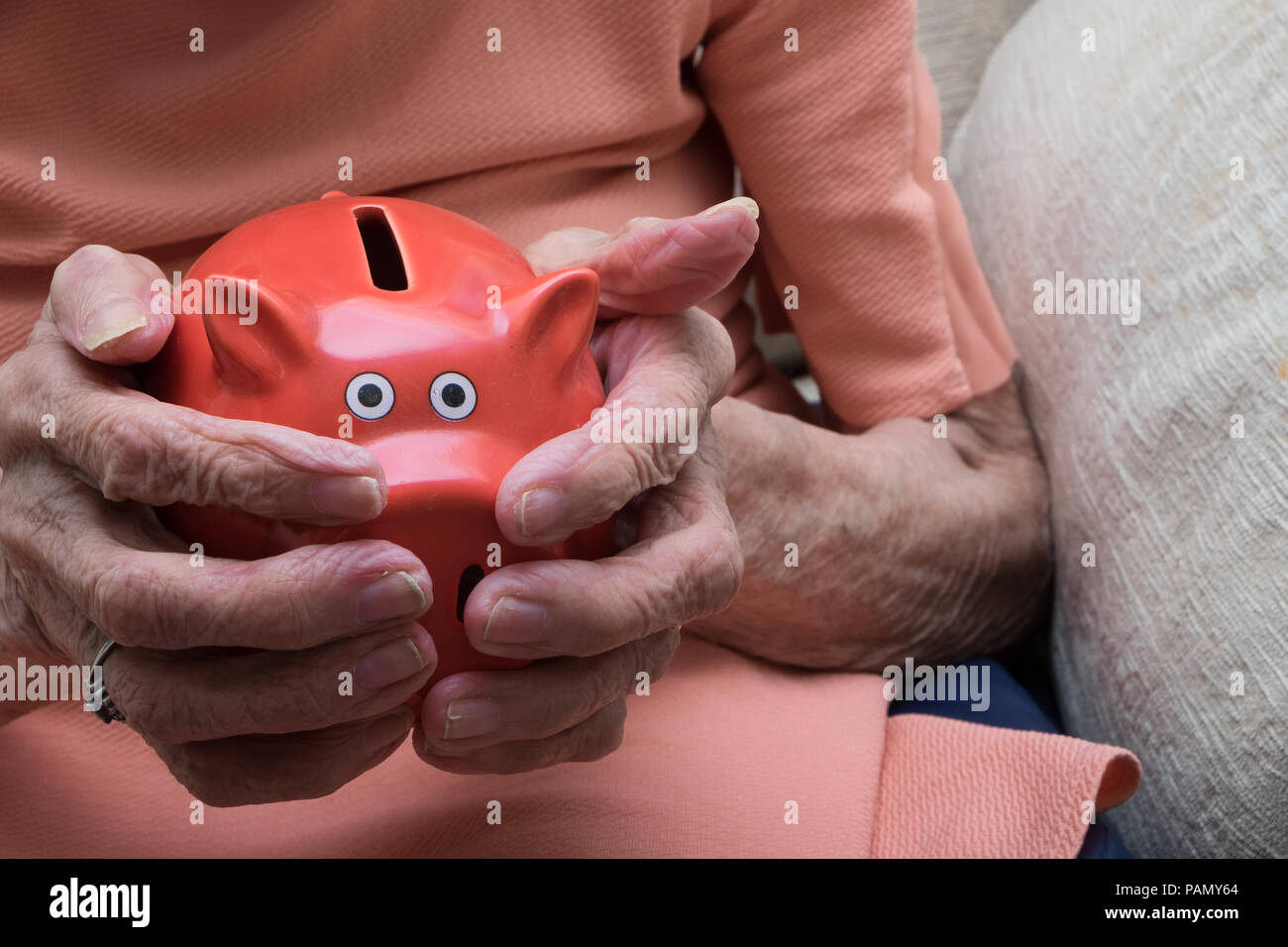Vieille dame rouge holding piggy bank Banque D'Images