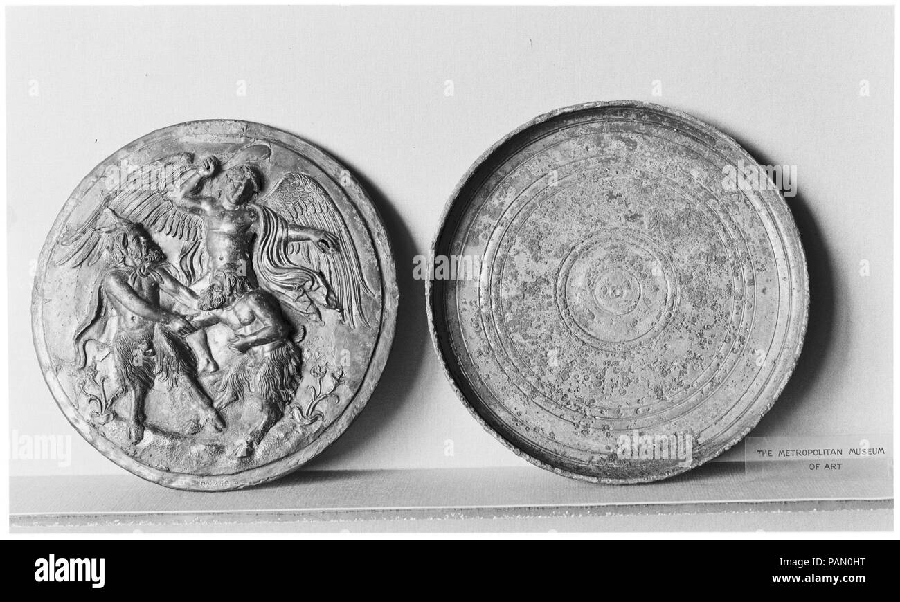 Boîte en bronze miroir. Culture : le grec. Dimensions : diamètre 5 1/4''. (13.3cm). Date : mi-4e siècle avant J.-C.. En relief, Eros intervenant dans querelle entre deux casseroles. Musée : Metropolitan Museum of Art, New York, USA. Banque D'Images