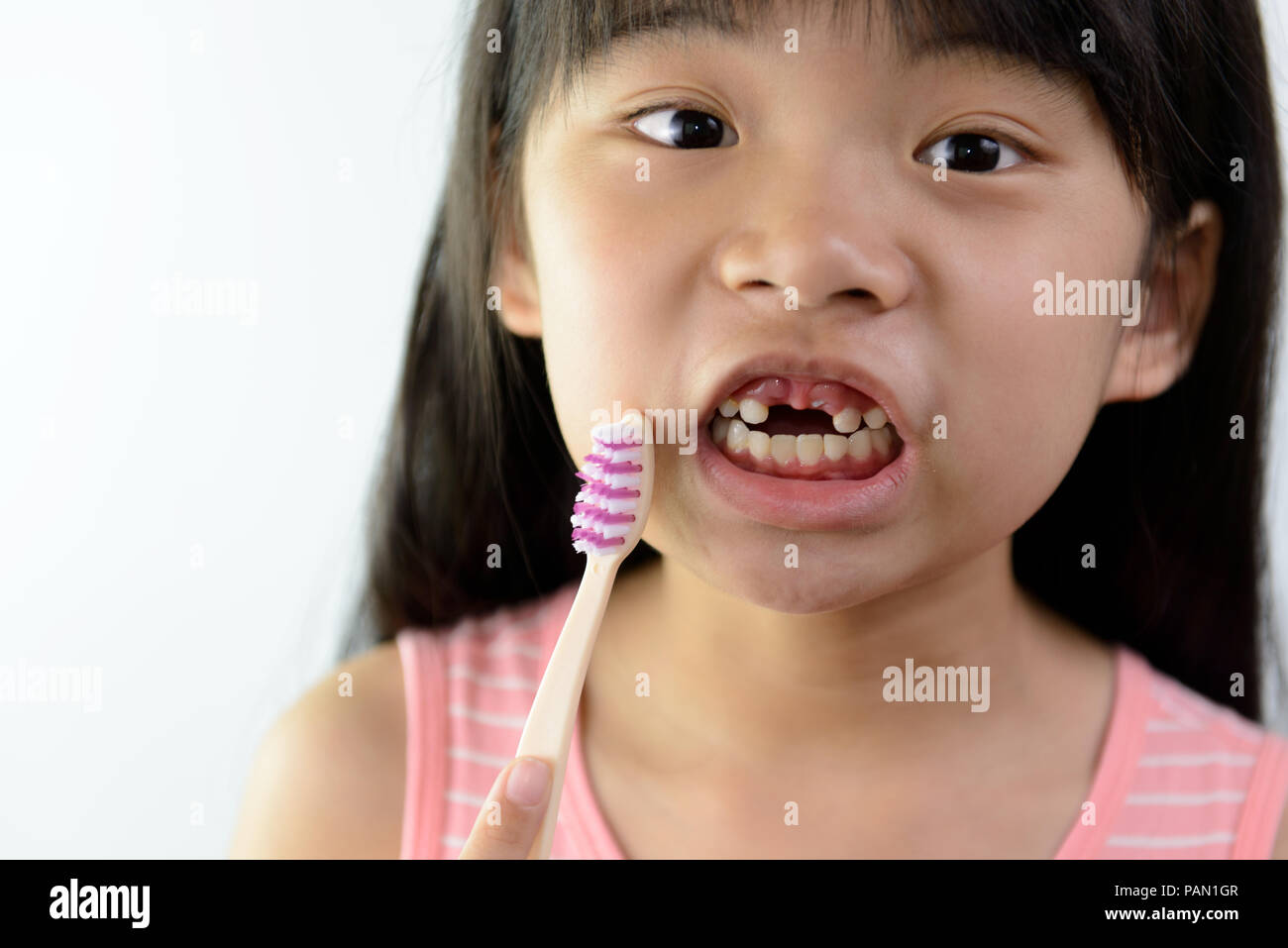 Little Asian girl sans dents de devant avec une brosse à dents Banque D'Images