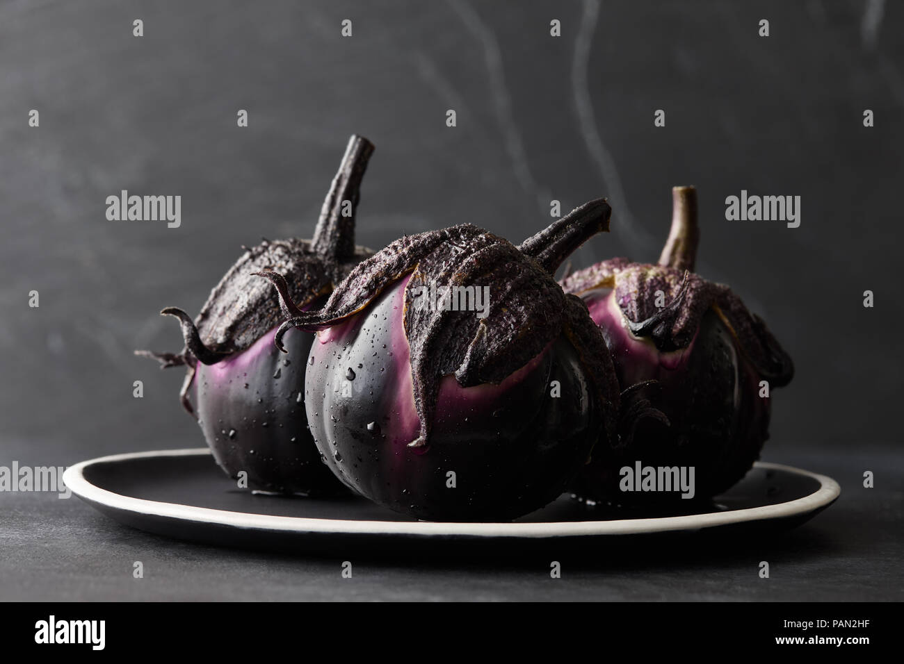 Aubergines fraîches avec de l'eau chute libre sur fond noir Banque D'Images