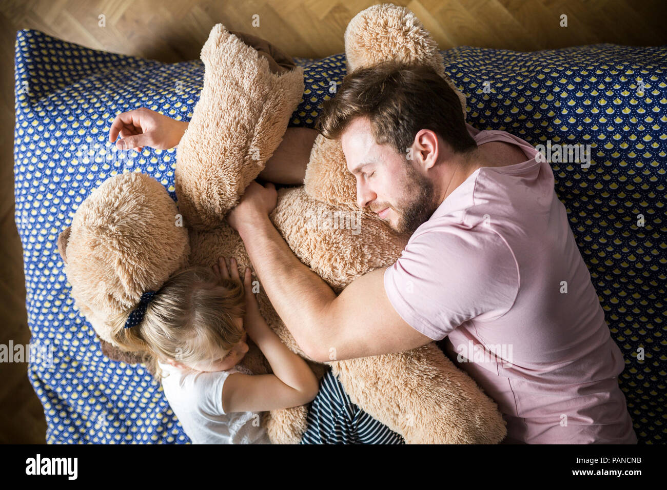 Père et fille de prendre une sieste, câlins avec ours Banque D'Images