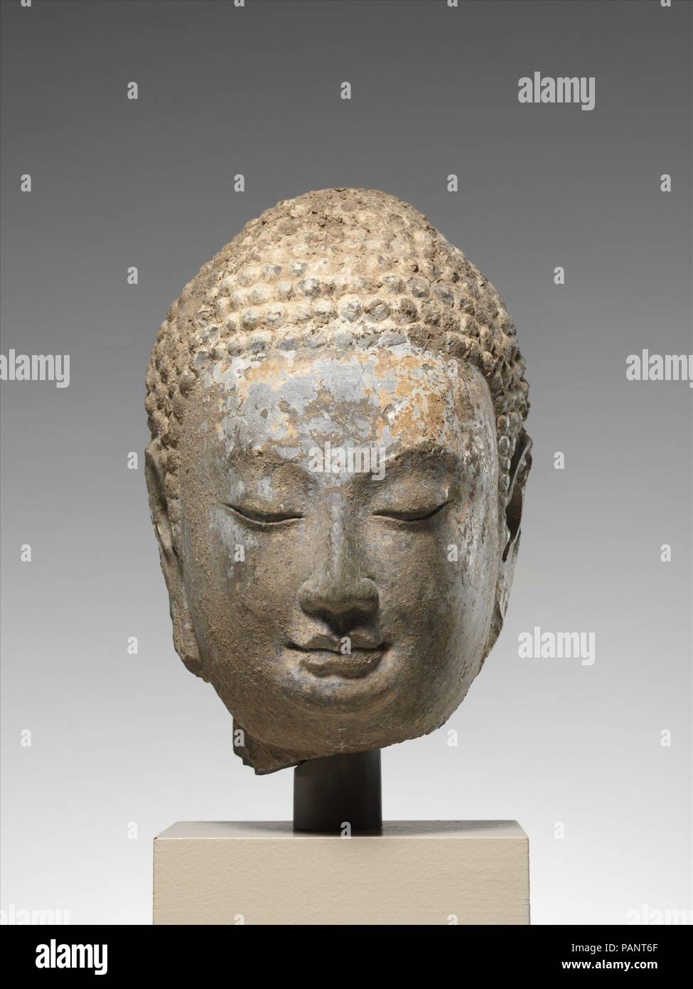 Tête d'un bouddha. Culture : la Chine. Dimensions : H. 9 1/2 in. (24,1 cm)  ; O. 6 1/4 in. (15,9 cm) ; D. 6 1/2 in. (16,5 cm). Date : milieu