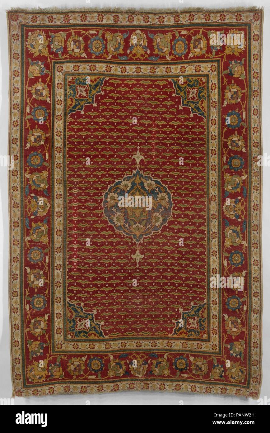 Tapis. Dimensions : Textile : H. 79 in. (200,7 cm) W. 48 dans. (121,9 cm) Mont : H. 84 3/4 in. (215.3cm) W. 55 3/4 in. (141,6 cm) D. 1/2 in. (1,3 cm). Date : ca. 1550. Ce tapis en laine présente une grande frontière avec la répétition de grandes fleurs, de l'élaboration d'une vaste surface décorée avec chintamanis répéter, la perle-comme spots qui étaient populaires dans la cour ottomane. Un médaillon circulaire occupe le centre, avec une fleur de lys comme motif à son haut et bas formant un axe vertical. La conception d'un médaillon central et de quatre médaillons-trimestre est dans decorat Banque D'Images