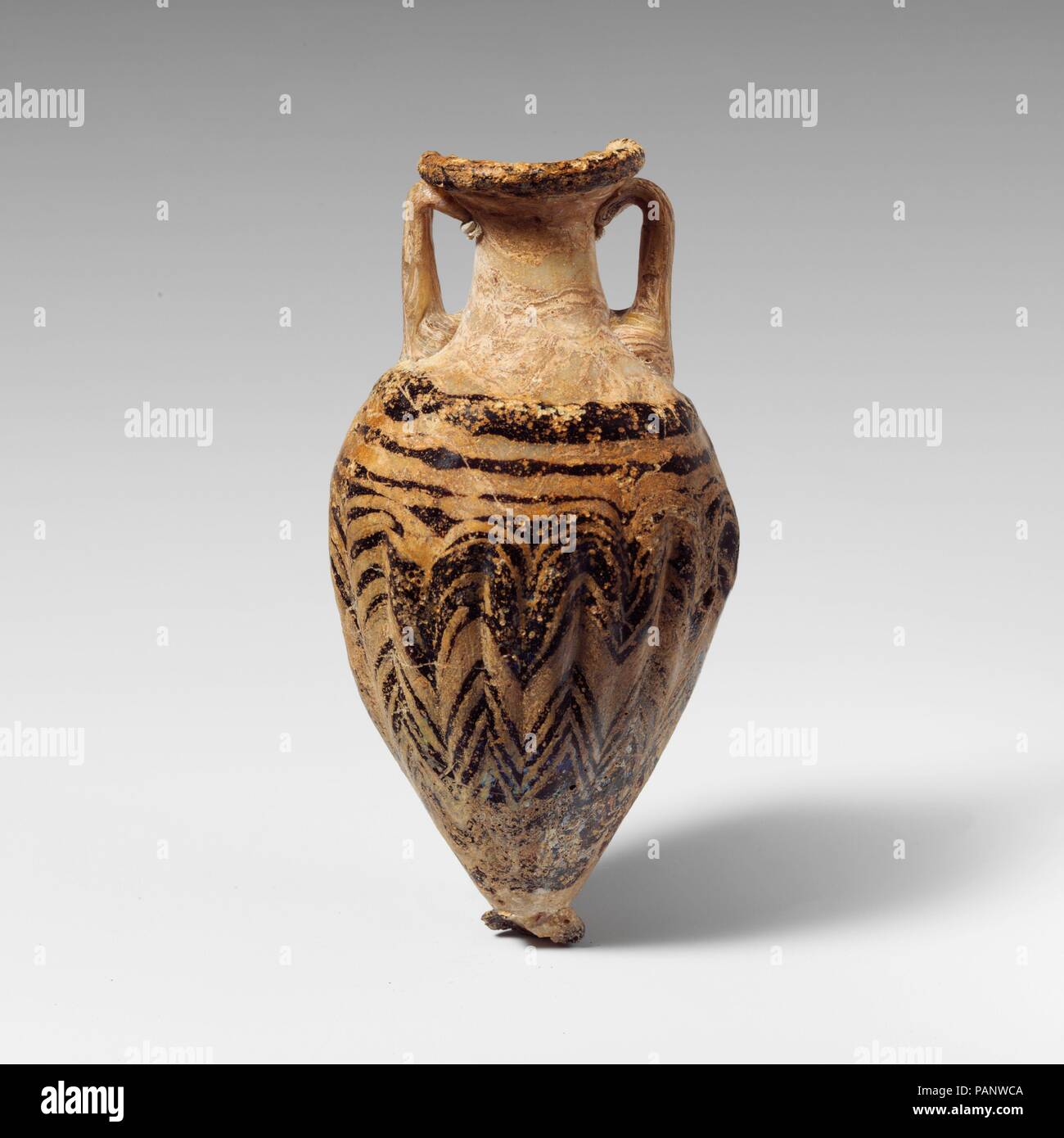 Amphoriskos en verre (flacon de parfum). Culture : le grec, l'Est de la Méditerranée. Dimensions : H. : 4 5/8 po. (11,8 cm). Date : fin 6ème-5ème siècle avant J.-C.. Opaque, blanc, avec poignées et base-bouton même couleur ; sentiers dans violet translucide. L'intérieur, large-disque-rim en pente ; cou cylindrique effilé vers le haut, large, oblique corps ovoïde allongé ; circulaire ; base-bouton avec bord arrondi ; deux poignées sangle verticale dressée à l'épaule, tourné dans, et au dessous du disque-rim. L'une d'épaisseur, arrondi à bord de piste jante-disque ; un autre sentier appliqué sur l'épaule et la série spirall Banque D'Images