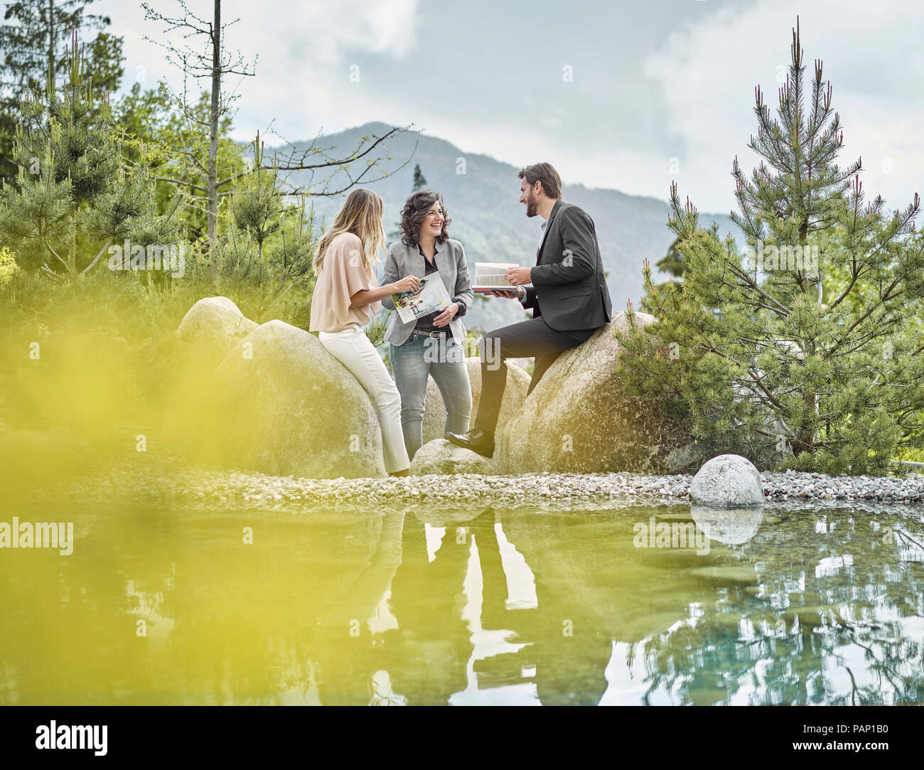 Smiling collègues avec des magazines ayant une pause à un pool Banque D'Images