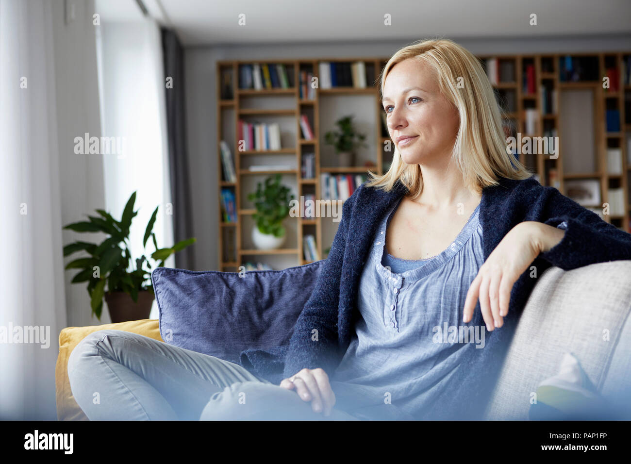Woman relaxing at home, sitting on couch Banque D'Images