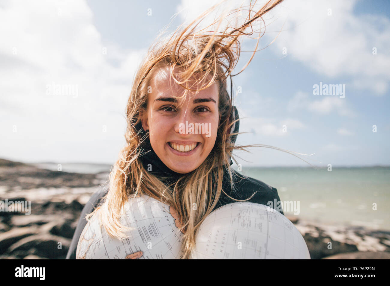 France, Bretagne, Landeda, portrait of smiling young woman holding parties d'un monde à l'autre Banque D'Images