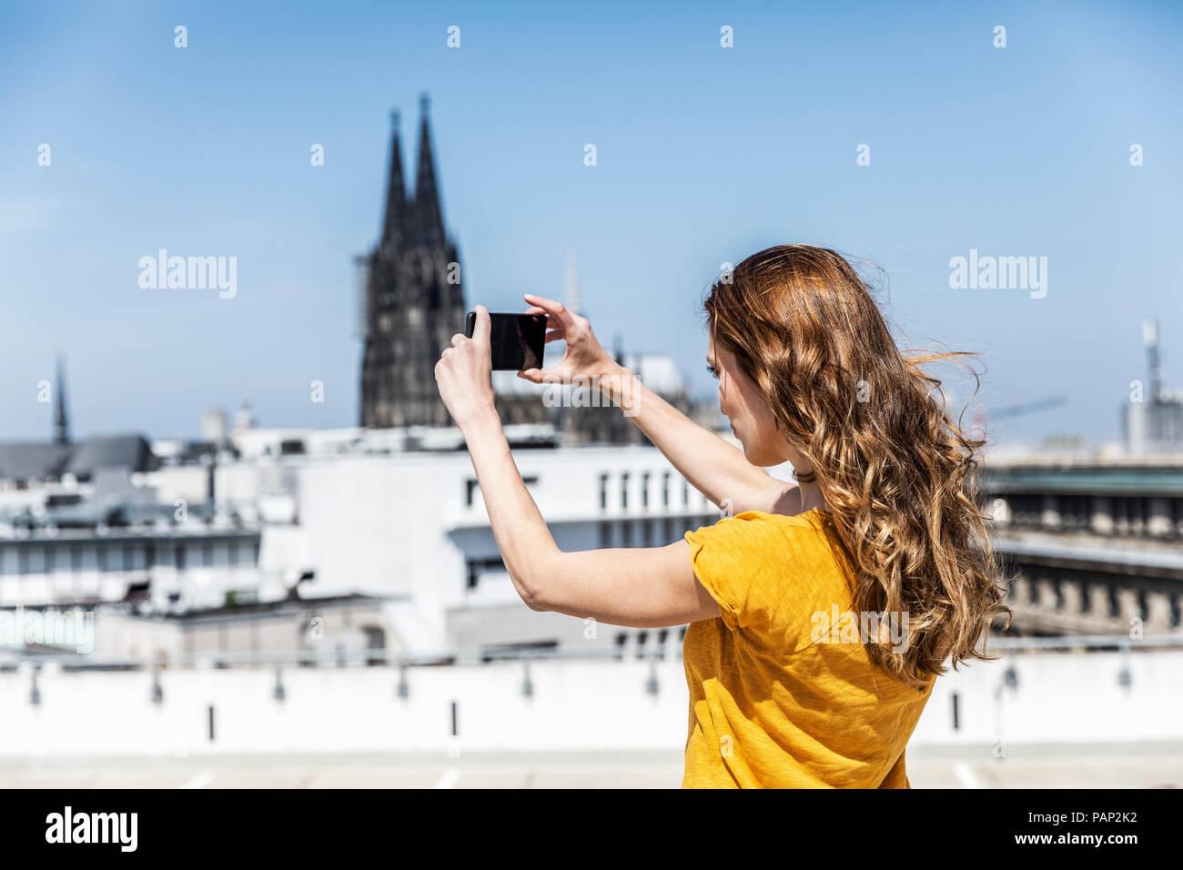 Allemagne, Cologne, woman taking photo avec toit-terrasse sur smartphone Banque D'Images