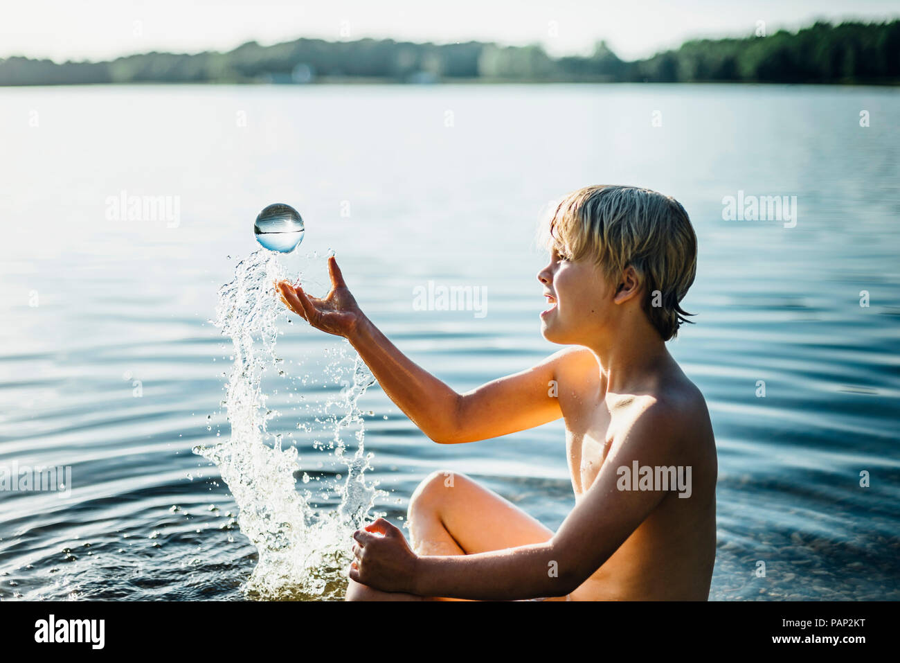 Garçon dans un lac à jouer avec sphère tansparent Banque D'Images