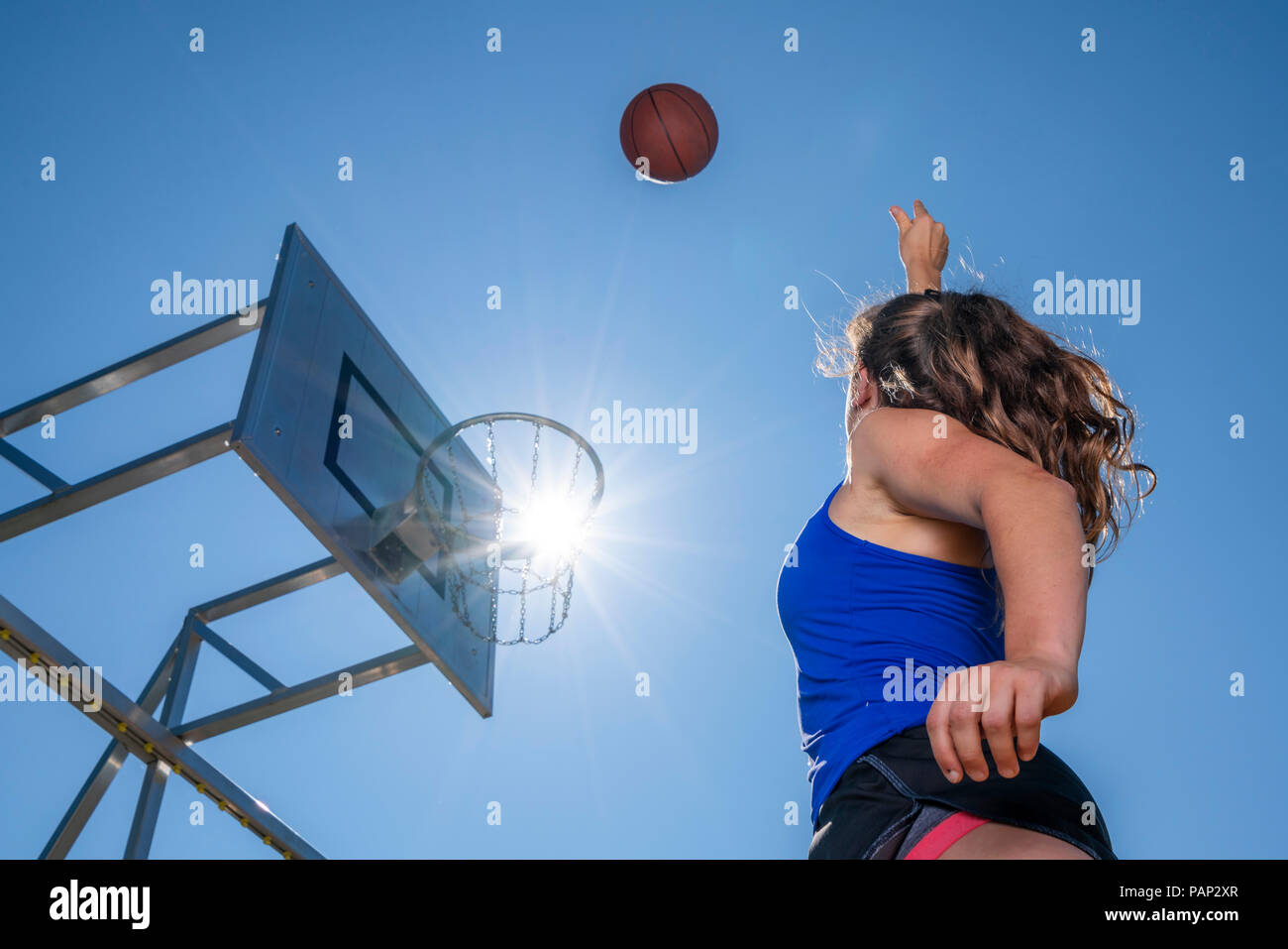 Jeune femme jouant au basket-ball, contre le soleil Banque D'Images