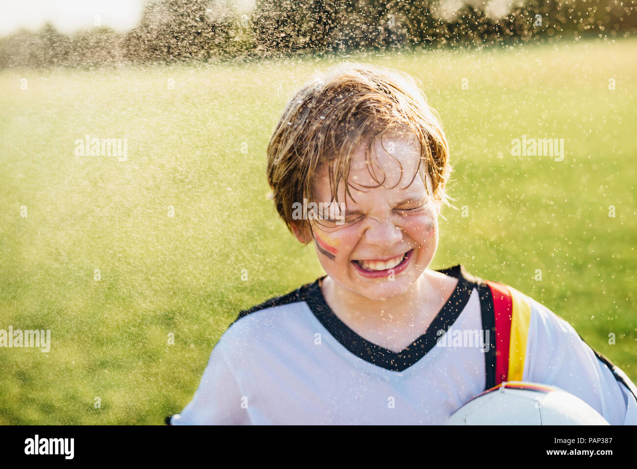 Boy wearing German soccer shirt debout dans les projections d'eau Banque D'Images
