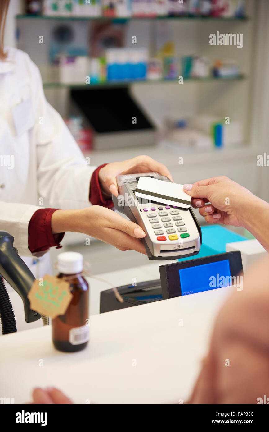 Le client paie par carte de crédit sans espèces dans une pharmacie Banque D'Images