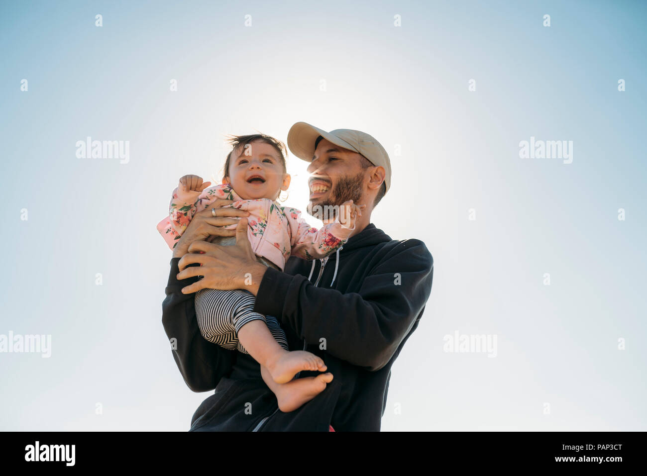 Laughing father holding baby girl à rétro-éclairage Banque D'Images