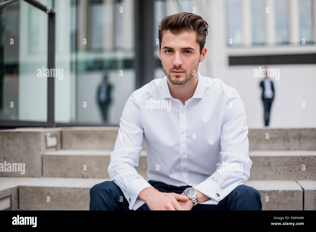 Portrait of young businessman sitting on stairs Banque D'Images