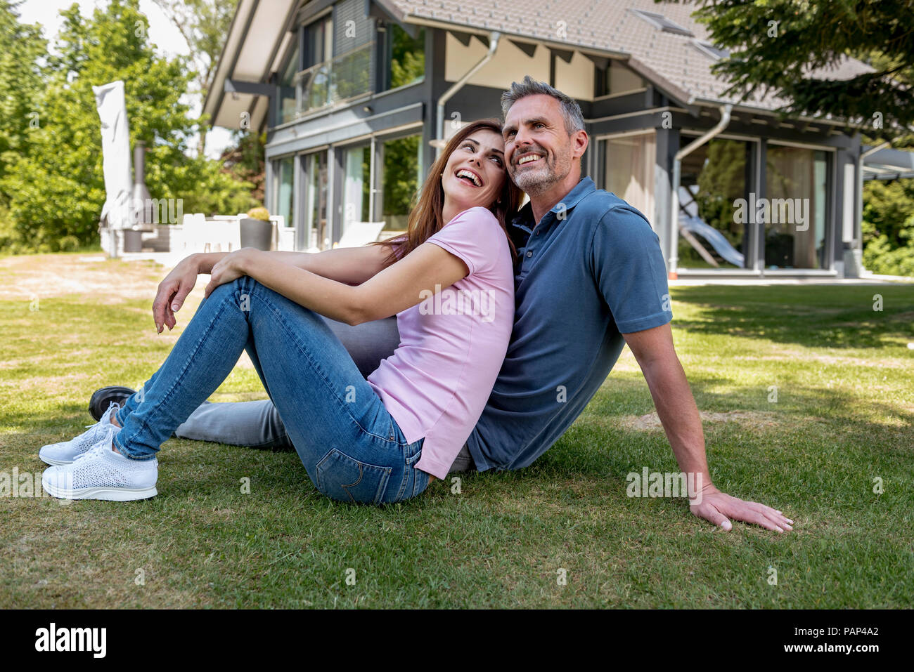 Heureux couple assis dans le jardin de leur maison Banque D'Images