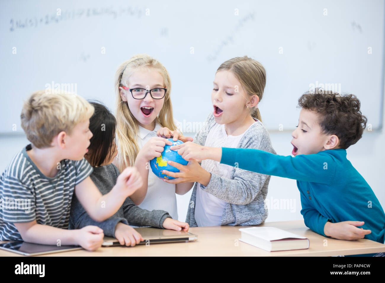 Les élèves heureux holding globe ensemble en classe Banque D'Images