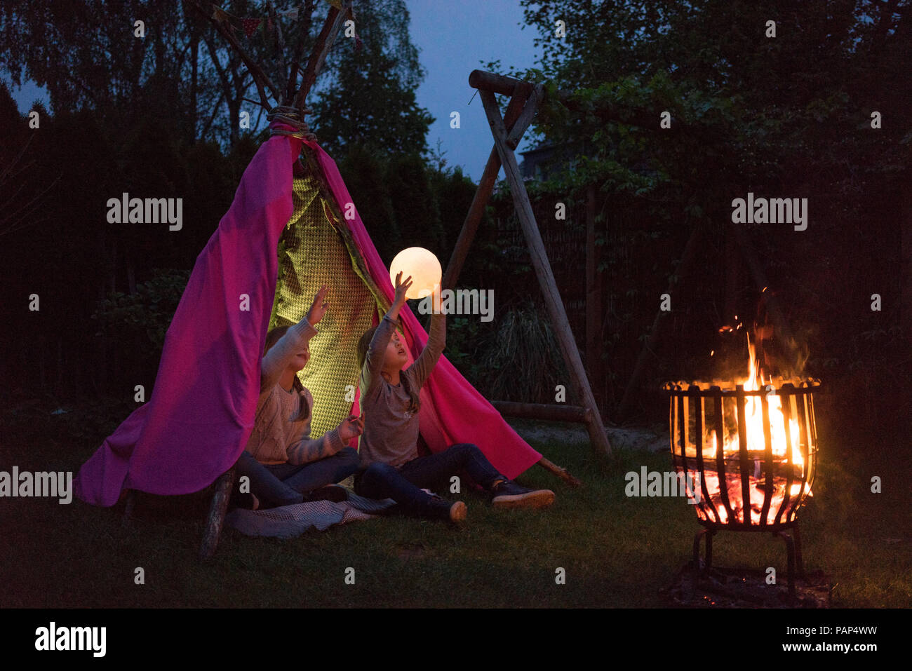 Deux filles debout en face de tipi, holding lampe comme lune Banque D'Images Deux filles debout en face de tipi, holding lampe comme lune Banque D'Images
