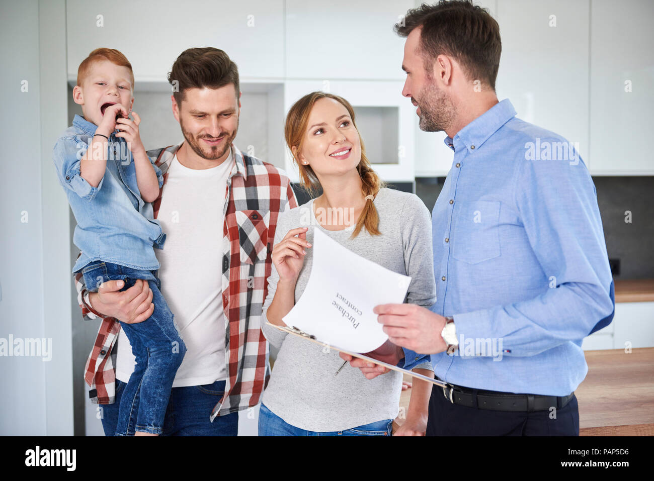 Famille et agent immobilier à parler dans nouvel appartement Banque D'Images