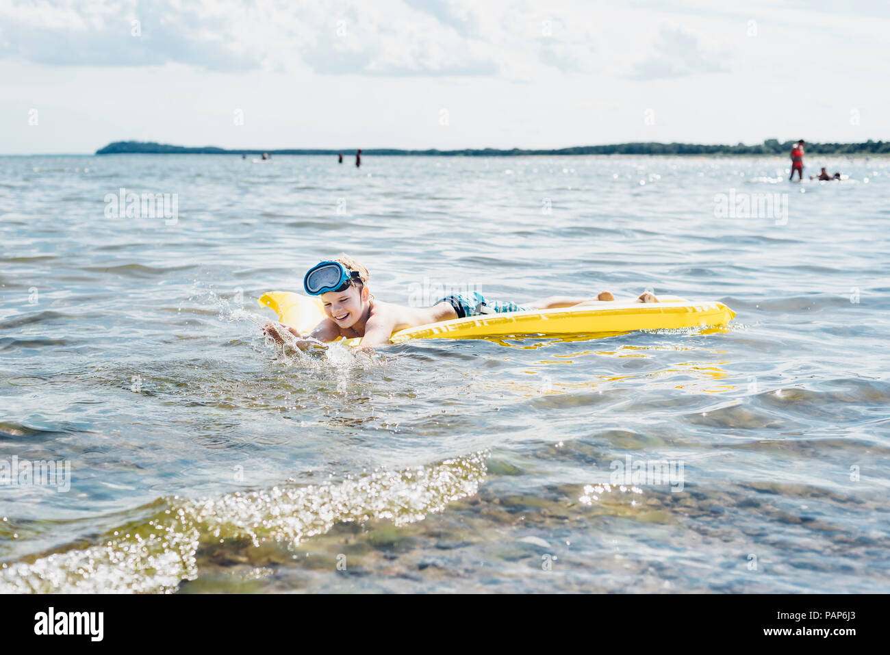 Garçon heureux flottant sur l'eau sur le matelas Banque D'Images