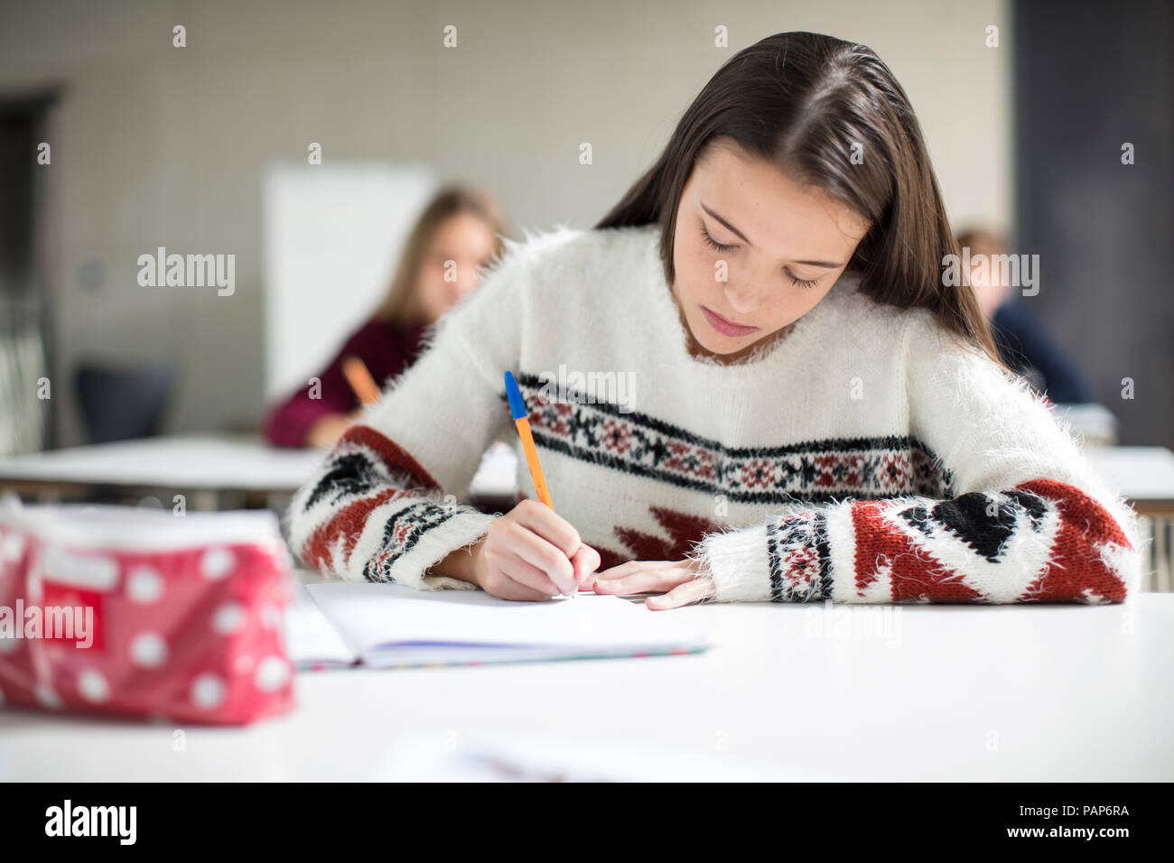 Teenage girl écrit dans un livre d'exercices en classe Banque D'Images