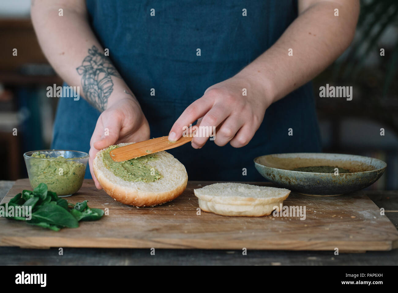 Femme préparant vegan burger, crème d'épandage sur pain Banque D'Images