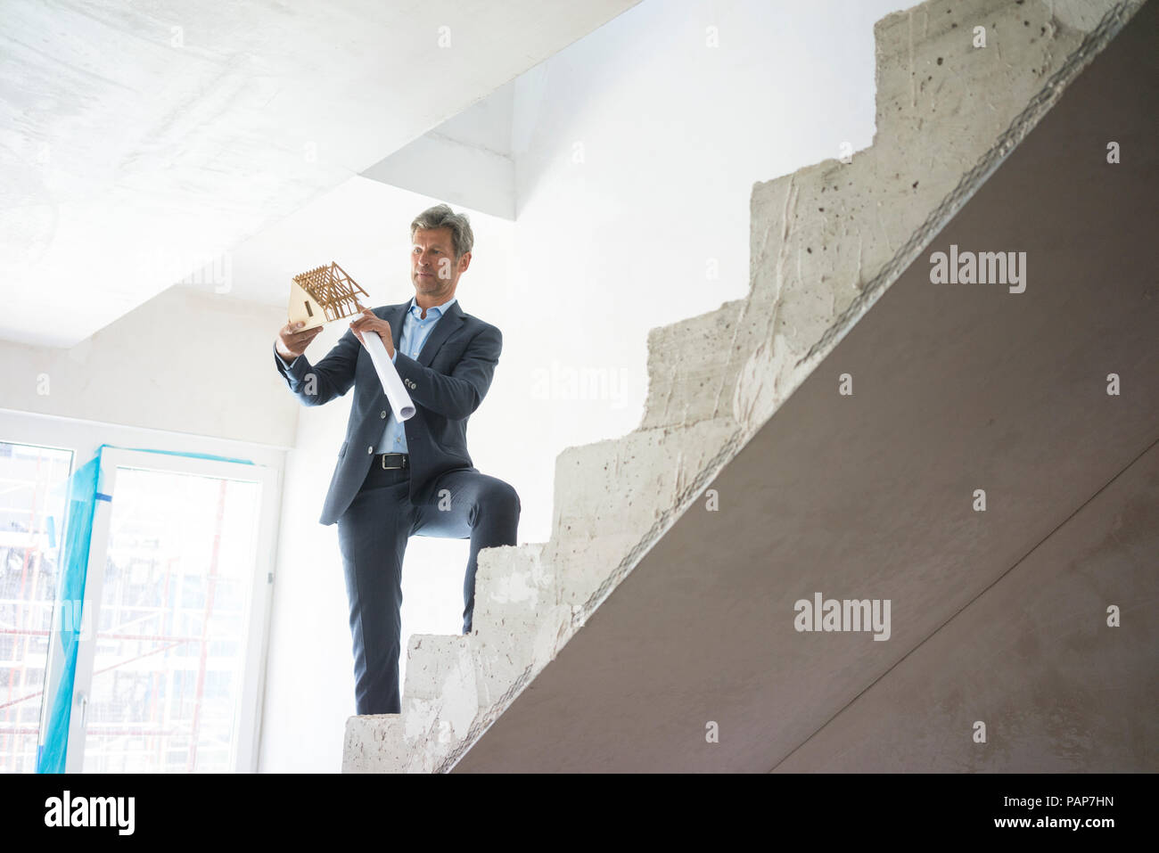 Modèle de maison architecte avec debout sur l'escalier dans le bâtiment en construction Banque D'Images Modèle de maison architecte avec debout sur l'escalier dans le bâtiment en construction Banque D'Images