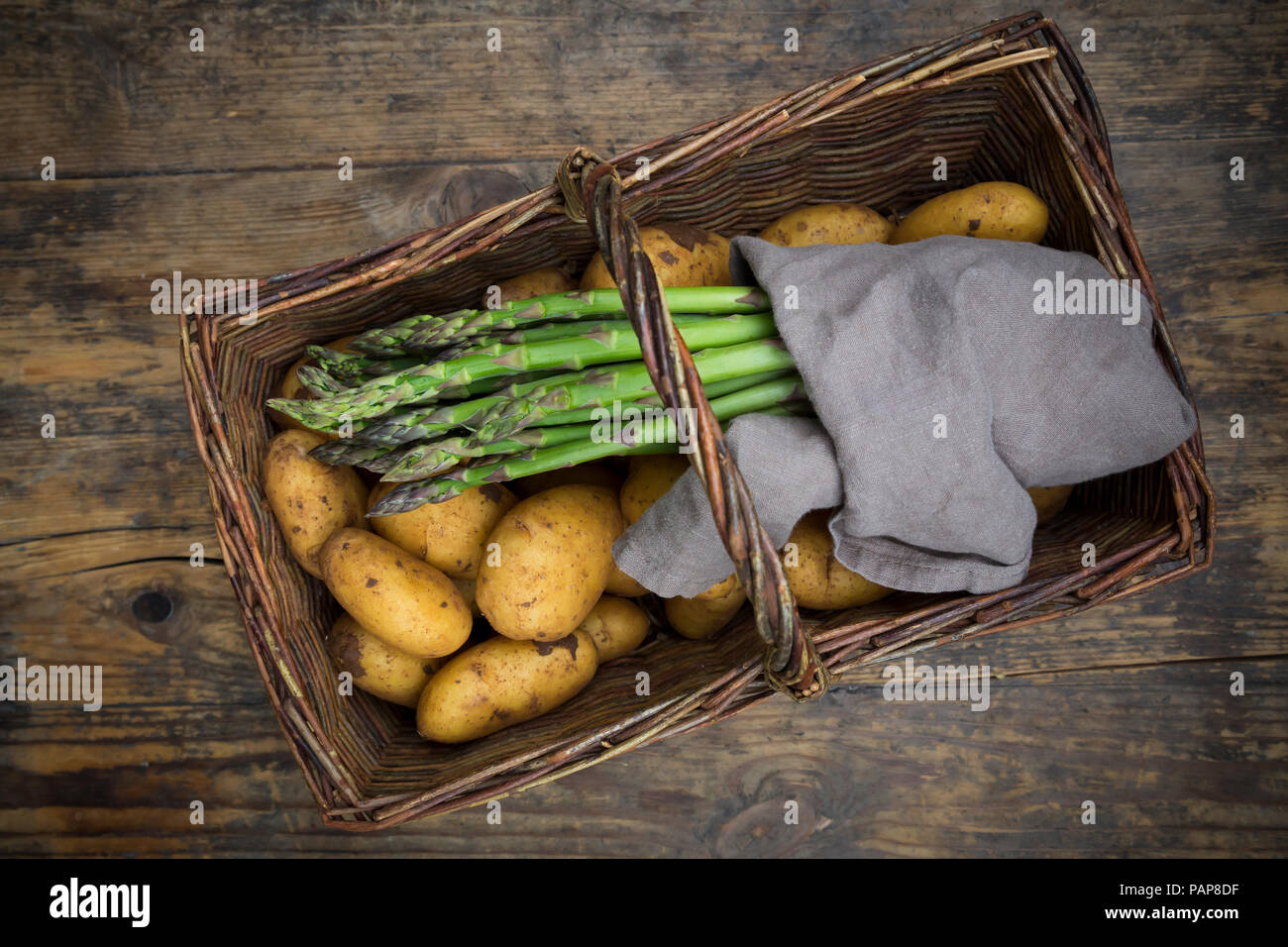 L'asperge verte biologique et les pommes de terre biologiques en wiccurbasket sur bois Banque D'Images