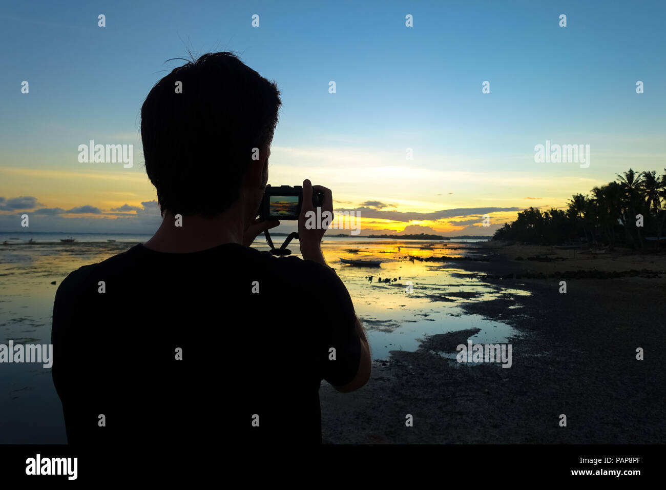 Homme photographe avec appareil photo, le tir dans le coucher du soleil sur une plage de l'île au cours de vacances - Aklan - Philippines, Boracay Banque D'Images
