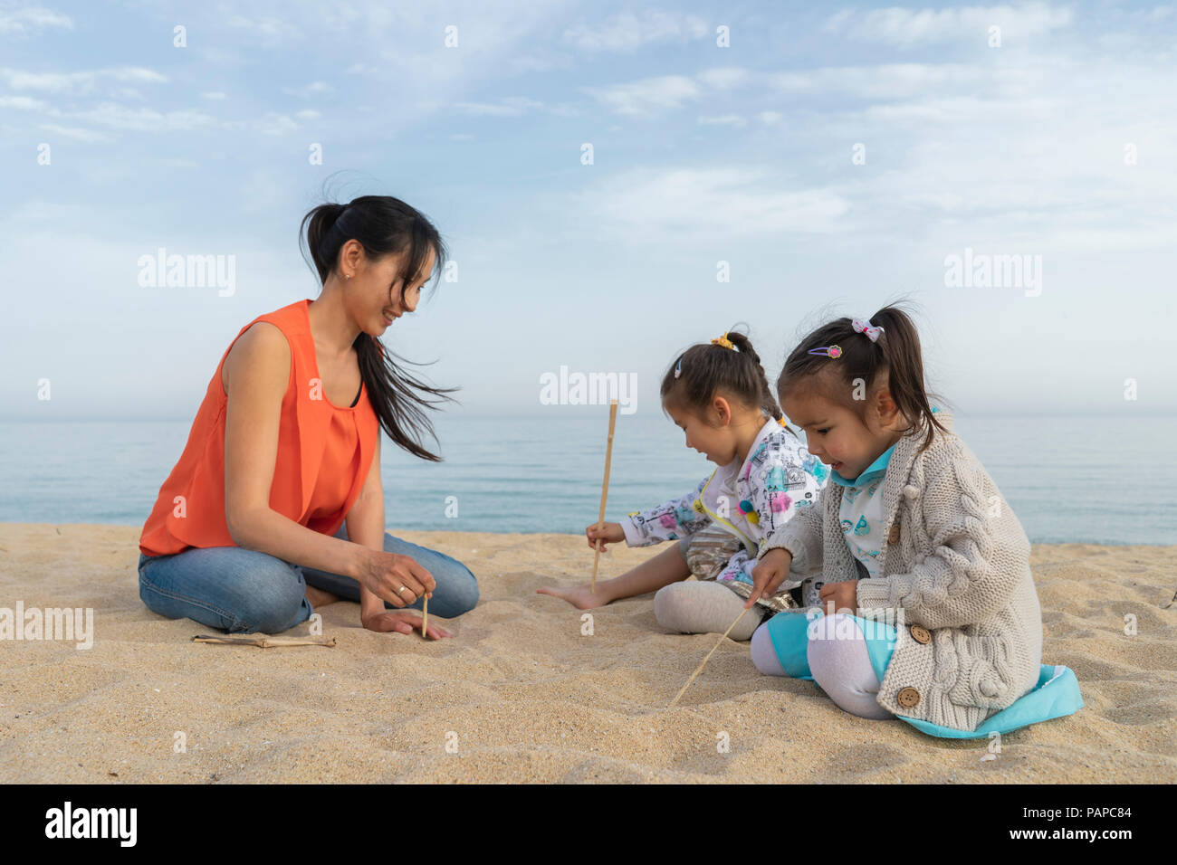 Mère de deux filles assis sur la plage Banque D'Images