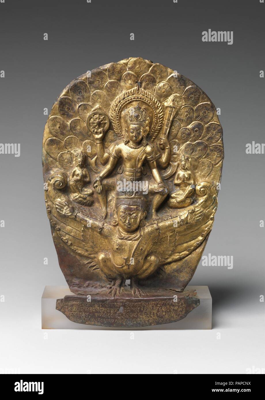 Vishnu équitation sur Garuda. Culture : le Népal. Dimensions : H. 16 1/2 in. (41,9 cm) ; W. 11 5/8 in. (29,5 cm) ; D. 3 3/8 in. (8,6 cm). Date : du 1004. Ce rare exemple précoce de Népalais le repoussé dépeint la dieu Vishnu en vol à cheval sur ses demi-oiseau, mi-humains, Garuda. Il affiche un disque flamboyant, un club, et d'une conque. Au-dessus de ses ailes sont minuscules chiffres de ses épouses. Vishnu est le premier ministre de la déité du nord de l'Inde Gupta clan, et Garuda leur symbole dynastique--une association royale qui s'est poursuivie avec l'Licchavi royaume du Népal. L'inscription se réfère ici à Vishnu Garudadhvaja (celui qui Banque D'Images