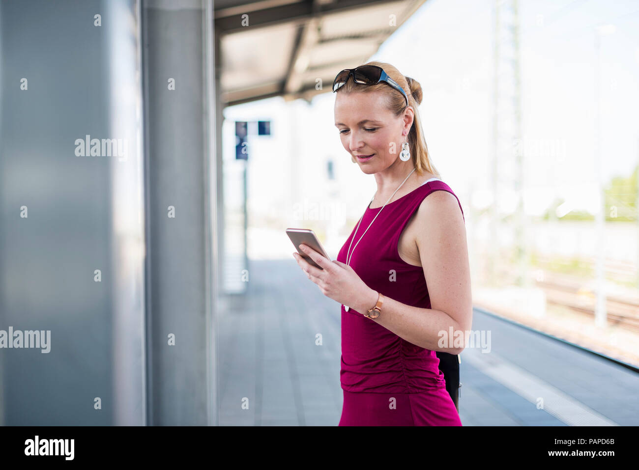 Smiling mature woman standing on platform looking at cell phone Banque D'Images